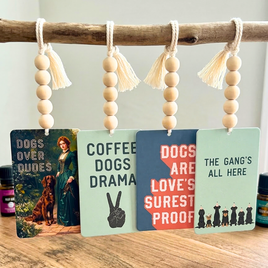 Set of four decorative cards with dog-themed sayings hanging from a branch on a wooden surface.